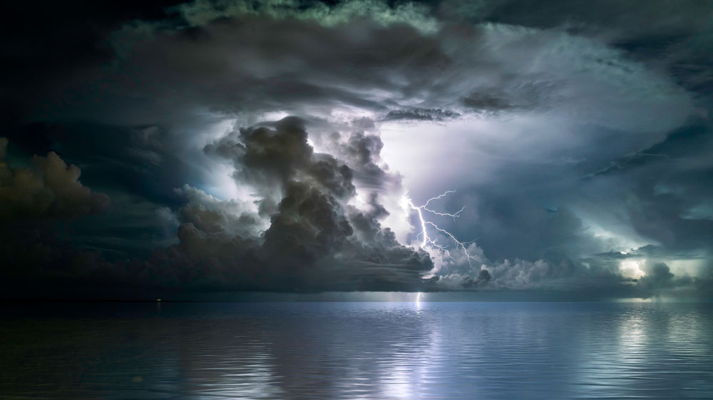 Storm clouds with a lightning strike over open water